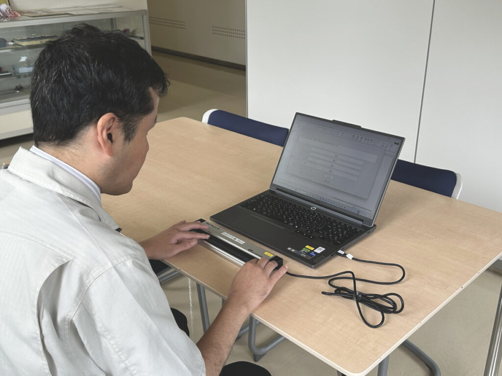 点字ディスプレイを使用してパソコンを読む男性。