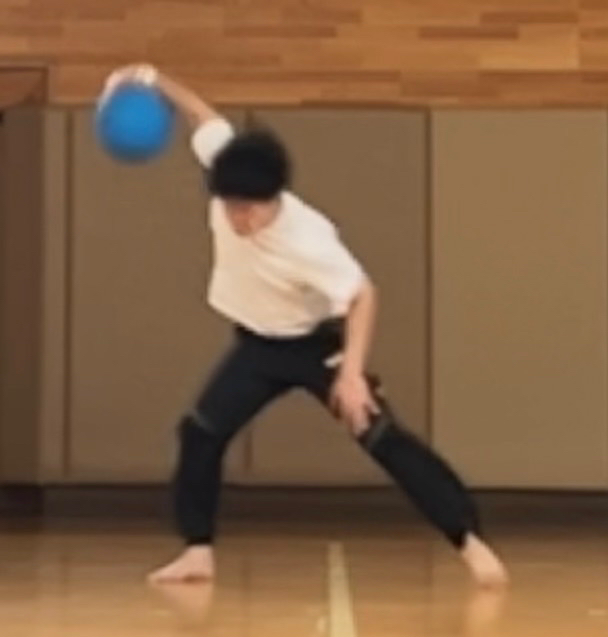 男性がゴールボールの投げのフォームをとっている。
